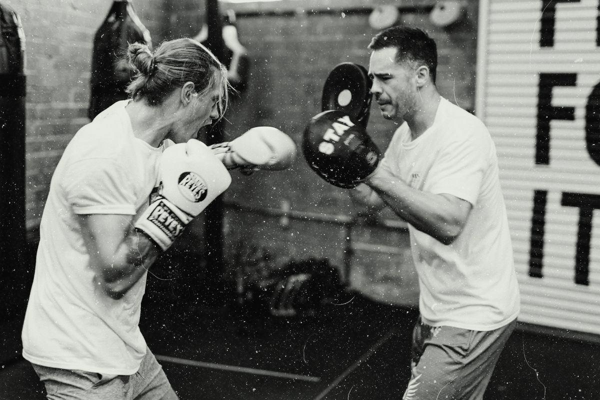 A coach holding pads for a boxer