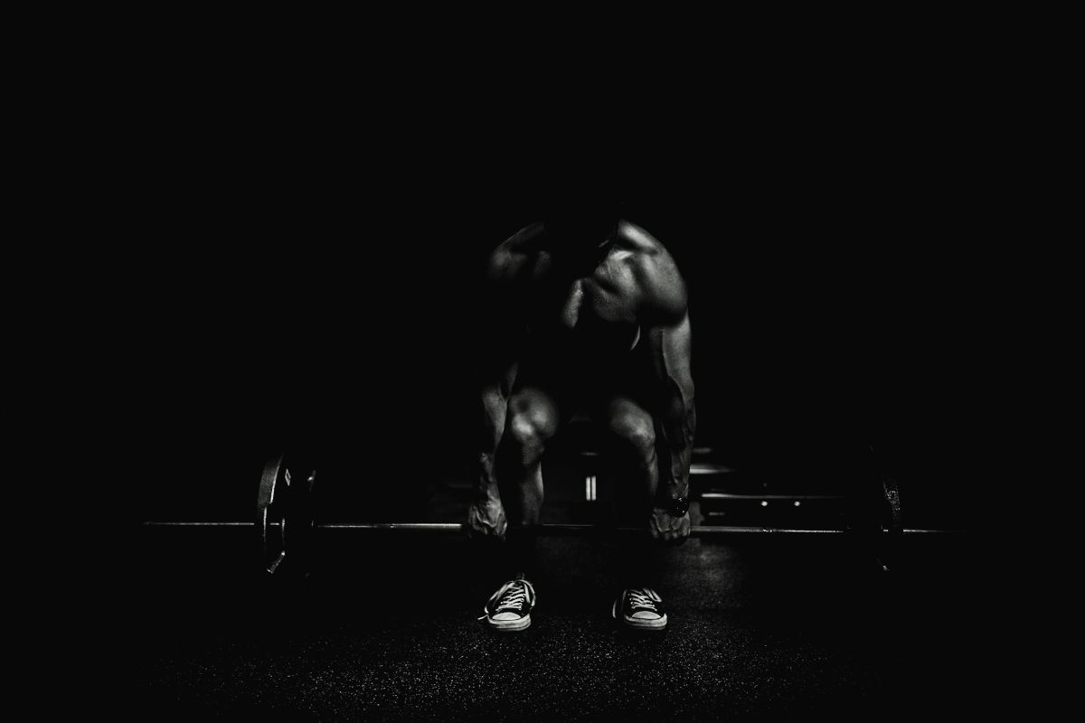 An athlete gripping a loaded barbell under a single light